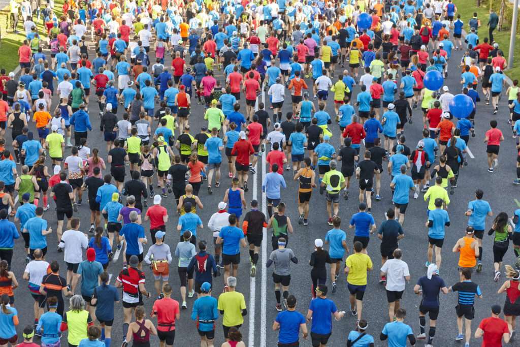 Maschsee Hannover - Eine große Gruppe farbenfroh gekleideter Läufer nimmt am ADAC Marathon Hannover 2025 teil. Die bunt gemischte Menge bewegt sich vorwärts, füllt die breite Straße, während sie in die gleiche Richtung läuft, und bildet so ein lebendiges Mosaik aus Farben. - maschseefest Hannover
