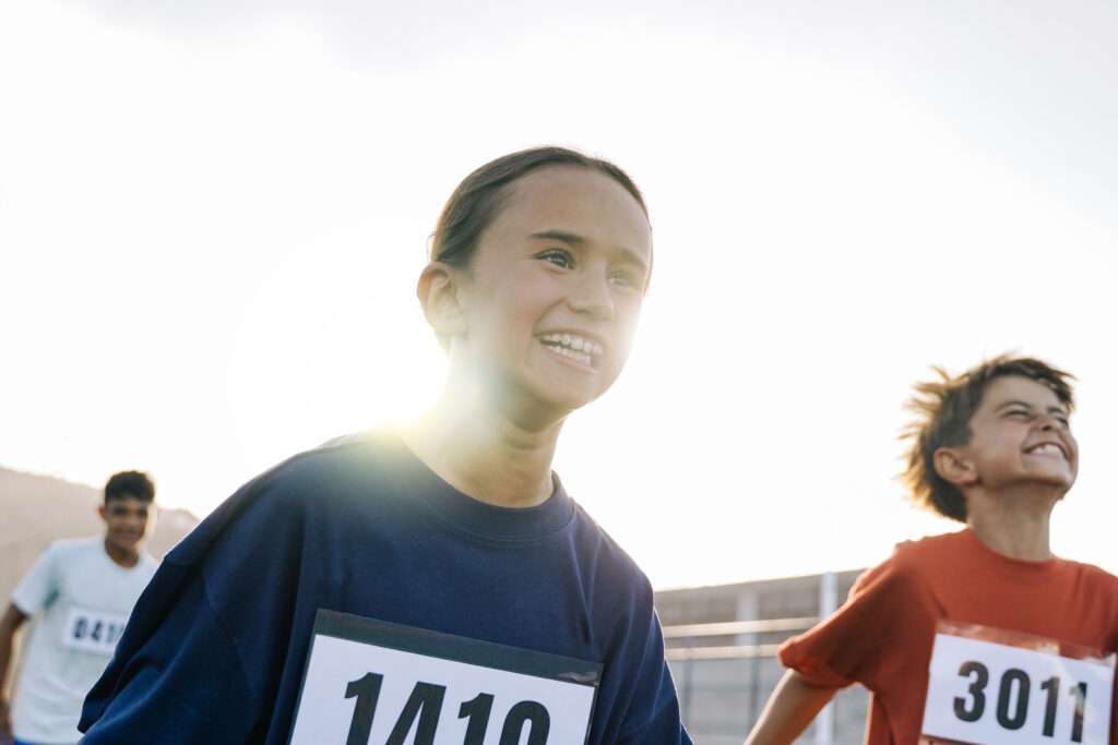 Maschsee Hannover - Drei junge Läuferinnen mit Startnummern am Trikot nehmen am ADAC Marathon Hannover 2025 teil. Die Sonne steht hell hinter ihnen und erzeugt einen Gegenlichteffekt. Sie wirken konzentriert und rennen zielstrebig. - maschseefest Hannover