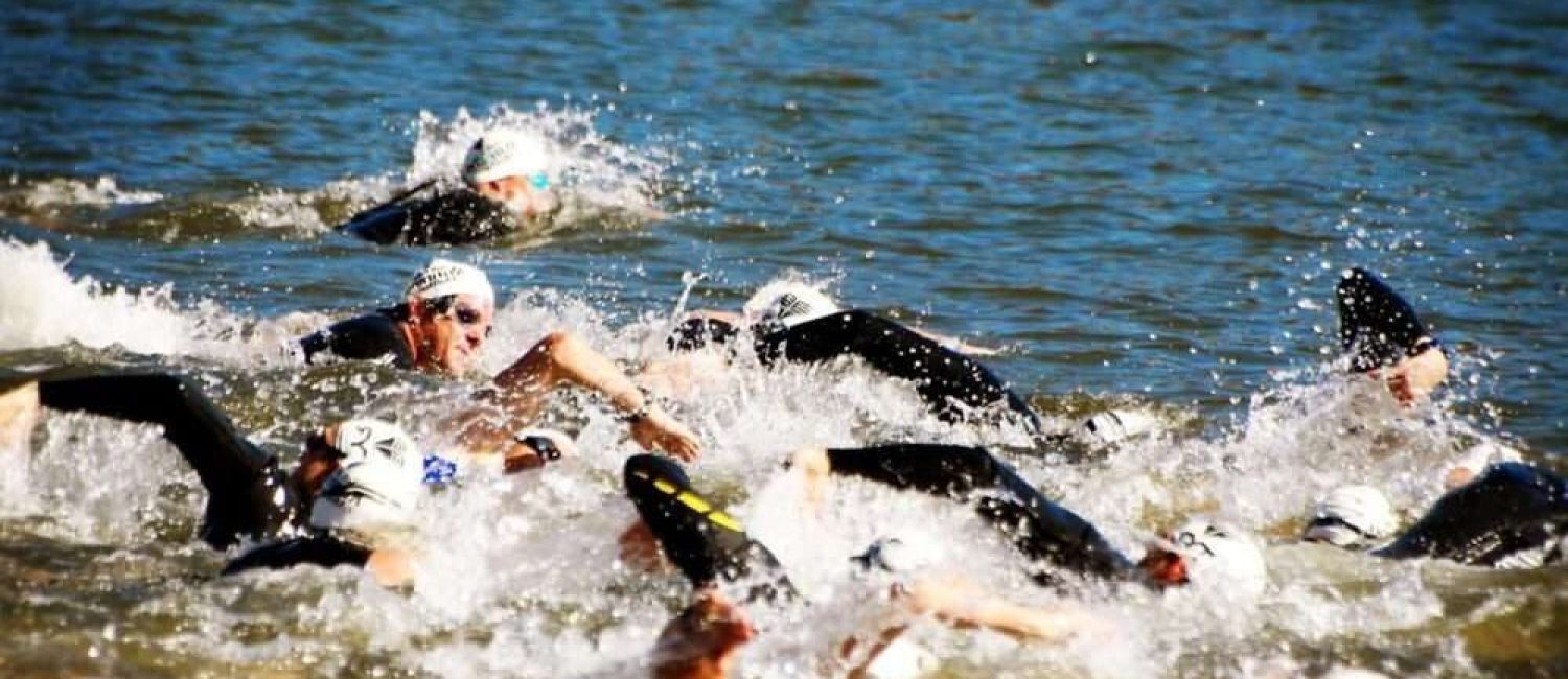 Maschsee Hannover - Eine Gruppe von Schwimmern in Neoprenanzügen und Badekappen liefert sich einen erbitterten Wettkampf im offenen Wasser des Hannover Triathlons und sorgt für Spritzer, während sie sich durch das leicht unruhige Wasser kämpfen. Die Szene fängt die Intensität und Anstrengung jedes Teilnehmers ein. - maschseefest Hannover