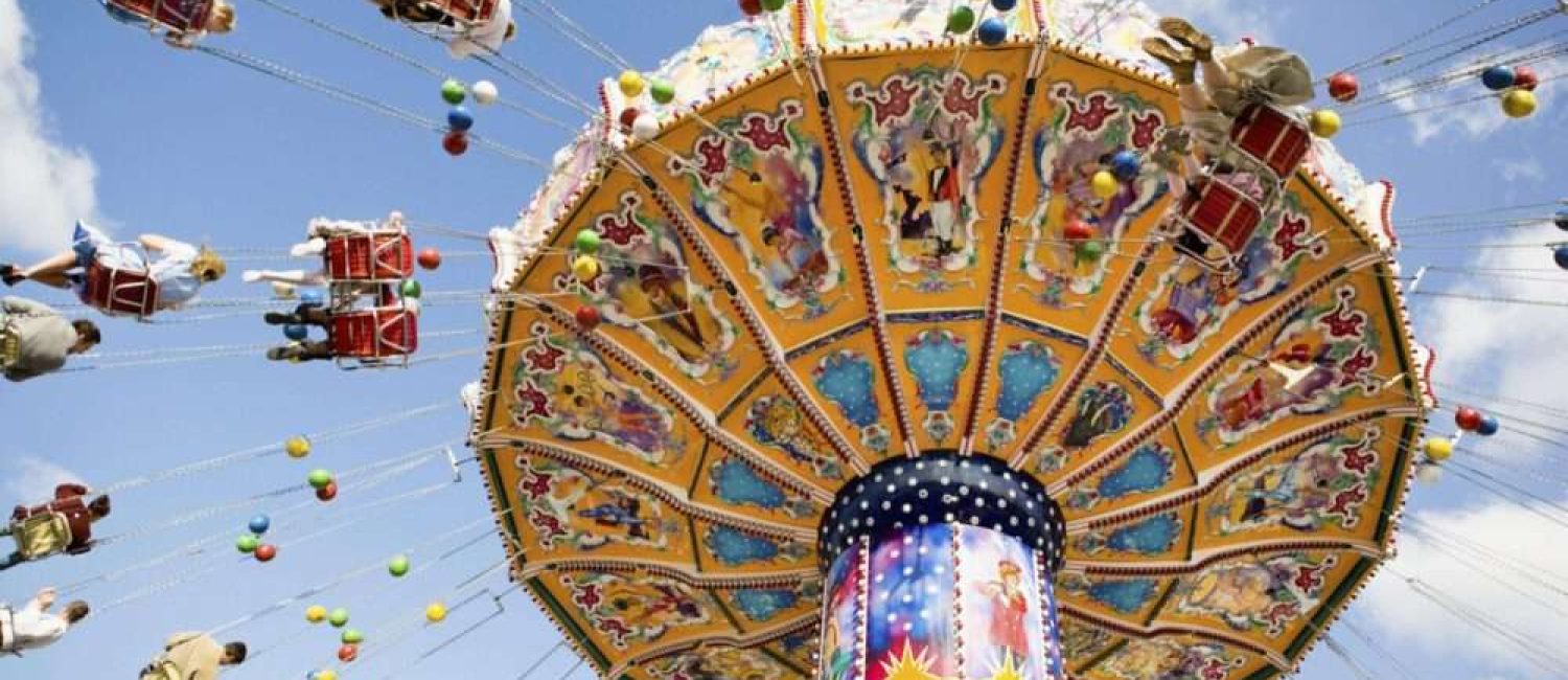 Maschsee Hannover – Auf einem farbenfrohen Karussell beim Schützenfest Hannover sitzen Menschen auf Stühlen, die an Metallketten befestigt sind. Das Karussell bietet lebendige Muster und Bilder vor einem blauen Himmel mit vereinzelten Wolken, während kugelähnliche Ornamente anmutig von oben herab schwingen. – maschseefest Hannover Maschsee Hannover - Auf einem farbenfrohen Karussell beim Schützenfest Hannover sitzen Menschen auf Stühlen, die an Metallketten befestigt sind. Das Karussell bietet lebendige Muster und Bilder vor einem blauen Himmel mit vereinzelten Wolken, während kugelähnliche Ornamente anmutig von oben herab schwingen. - maschseefest Hannover
